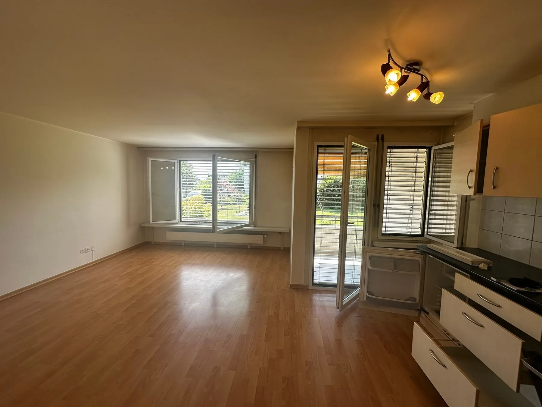 Wohnbereich mit integrierter Küche und Zugang zum Balkon